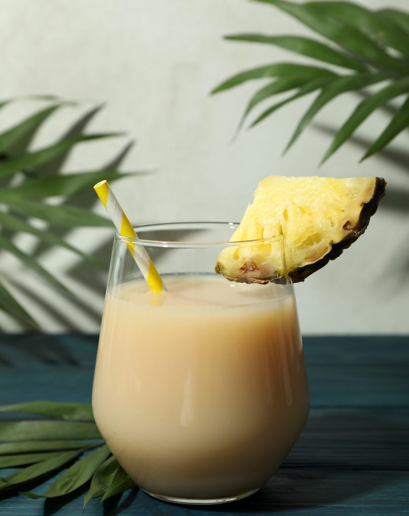 Pina colada cocktail on blue wooden table.